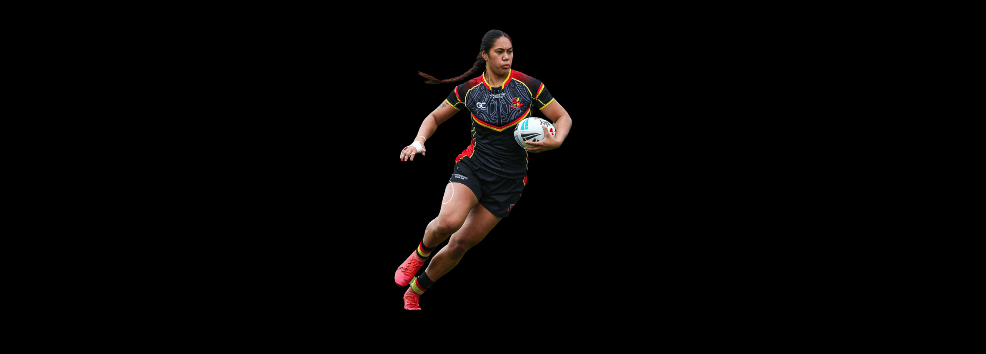 A female rugby player in a black, red, and yellow jersey runs while holding a rugby ball against a solid black background.